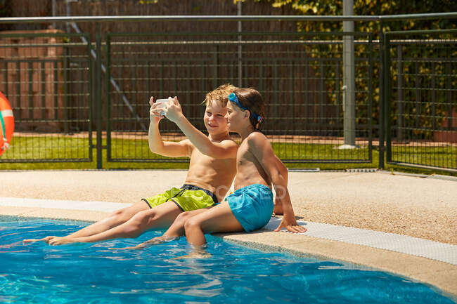 Мальчики у бассейна делают селфи — стоковое фото