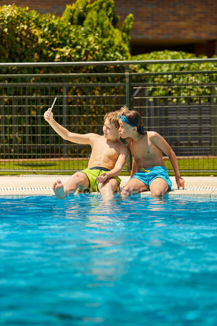 Garçons au bord de la piscine prenant selfie — Photo de stock
