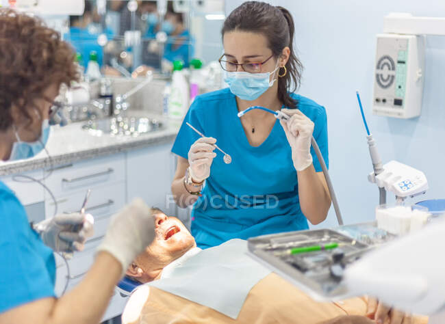 Zahnärzte in Maske legen Siegel in offenen Mund des Patienten im Stuhl — Stockfoto