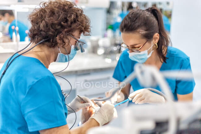 Стоматологи в маске кладут печать в открытый рот пациента в кресле — стоковое фото