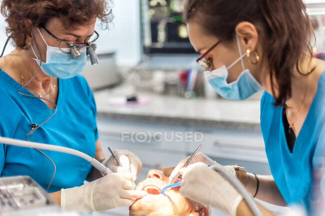 Zahnärzte in Maske legen Siegel in offenen Mund des Patienten im Stuhl — Stockfoto