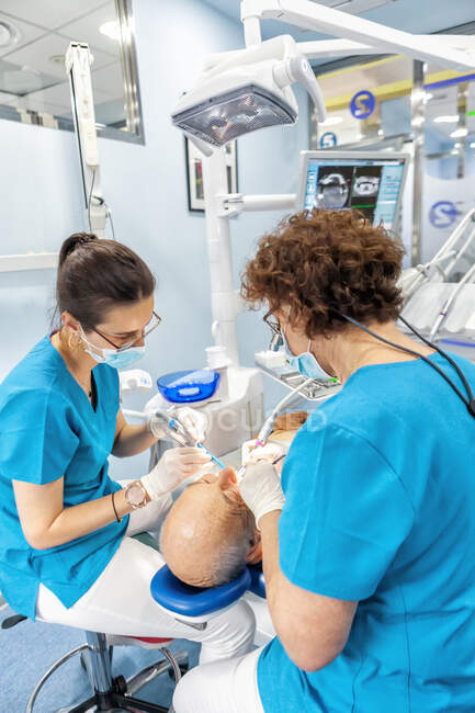 Стоматологи в маске кладут печать в открытый рот пациента в кресле — стоковое фото