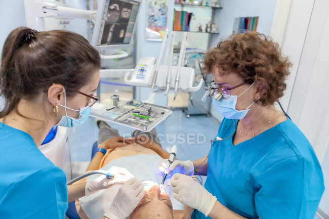 Стоматологи в масці кладуть пломбу у відкритий рот пацієнта в крісло — стокове фото