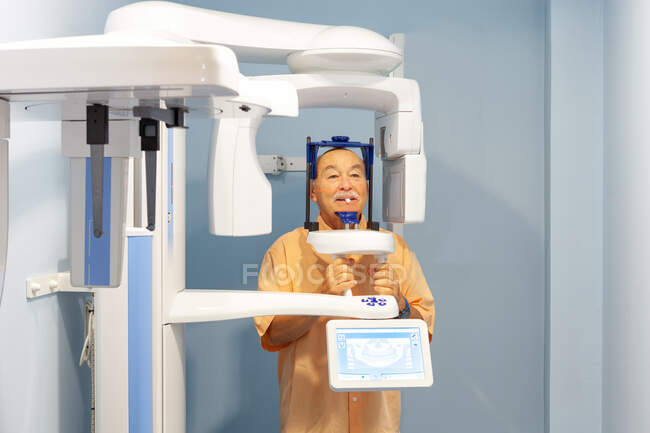 Vecchio in abiti protettivi speciali prendere i raggi X in gabinetto dentale — Foto stock