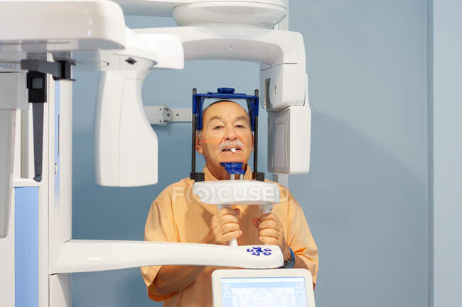 Vieil homme en vêtements de protection spéciale prenant des rayons X dans l'armoire dentaire — Photo de stock
