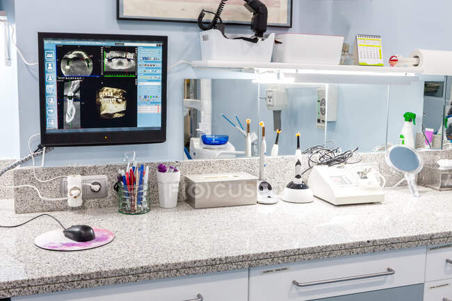 Monitor mit Bildern von Zähnen und Schreibwaren auf dem Tisch in der Zahnarztpraxis — Stockfoto