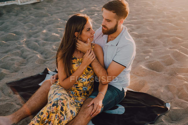 Jóvenes enamorados ligándose en la playa en la romántica noche de atardecer - foto de stock
