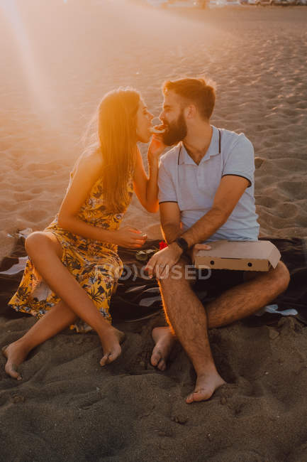 Bearded uomo amoroso e donna dai capelli lunghi mangiare insieme pizza alla luce del sole — Foto stock