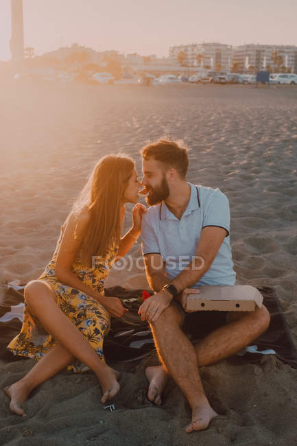 Barbu amoureux homme et femme aux cheveux longs manger ensemble pizza dans la lumière du soleil — Photo de stock