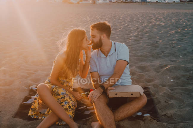 Bearded uomo amoroso e donna dai capelli lunghi mangiare insieme pizza alla luce del sole — Foto stock