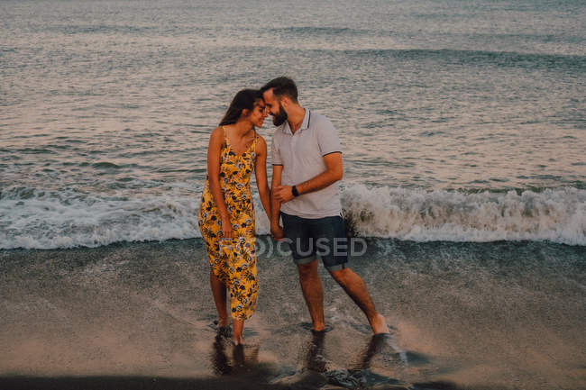 Любящий мужчина обнимает очаровательную женщину на берегу моря — стоковое фото