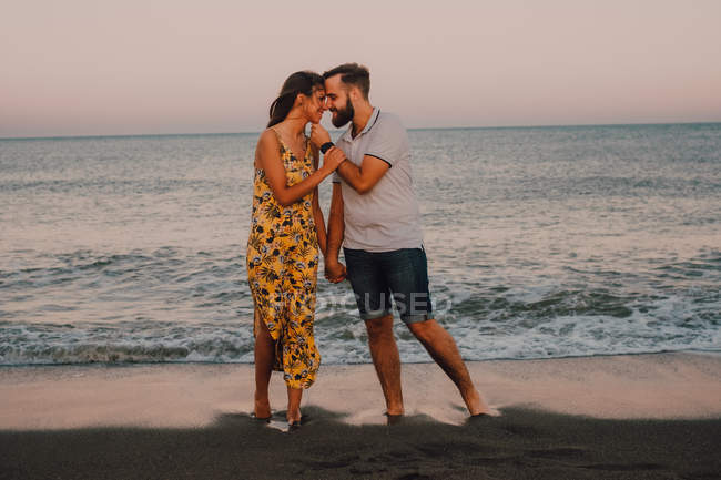 Любящий мужчина обнимает очаровательную женщину на берегу моря — стоковое фото
