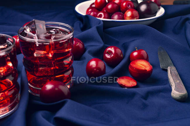 Bebida roja cerca de frutas frescas en tela azul - foto de stock