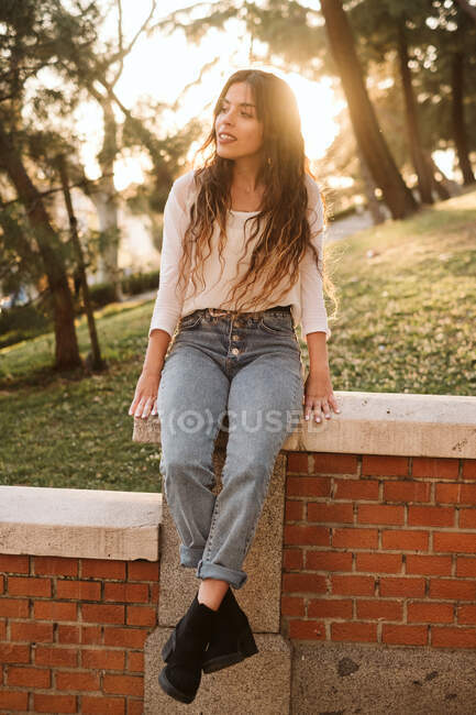 Hübsche junge Frau in lässigem Outfit lächelt und blickt an einem sonnigen Tag in der City Street in die Kamera — Stockfoto