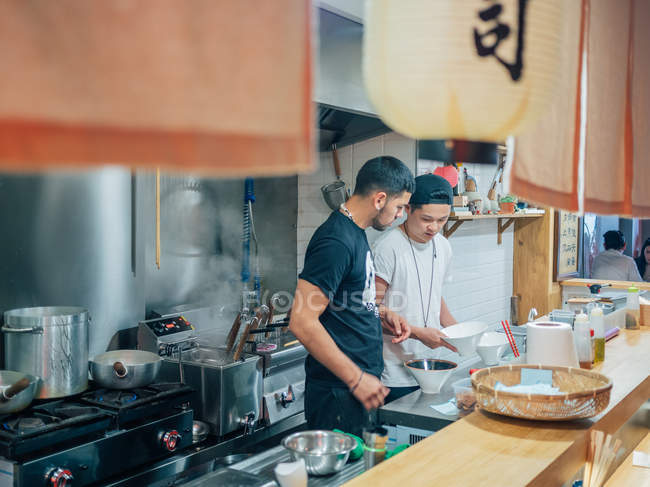 Von oben aus der Küche mit jungen Männern, die in einem orientalischen Restaurant japanisches Gericht Ramen kochen — Stockfoto