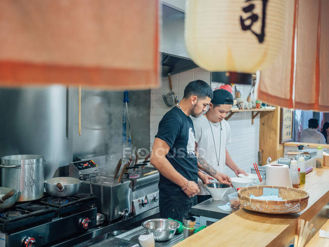 From above of kitchen with young men cooking Japanese dish ramen in oriental restaurant — Stock Photo