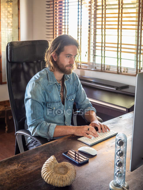 Людина використовує комп'ютер в інтер'єрі квартири — стокове фото