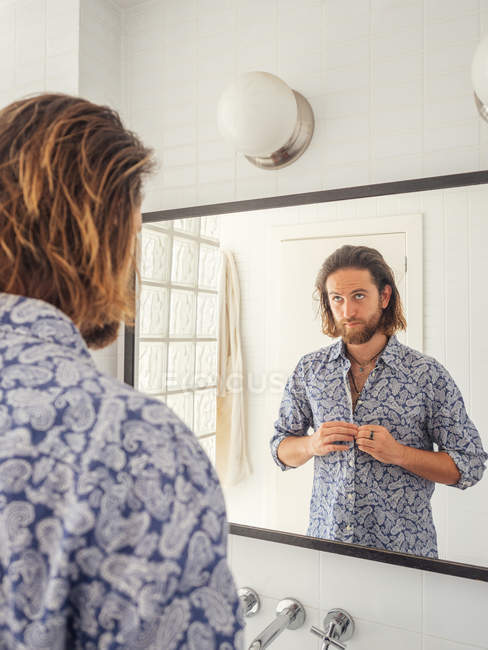Handsome young man checking hairstyle in mirror reflection — Stock Photo