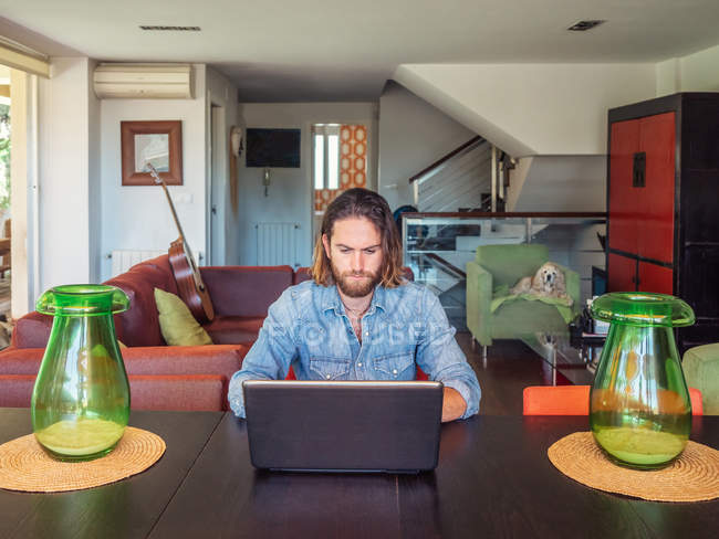 Uomo concentrato che utilizza il computer in appartamento — Foto stock