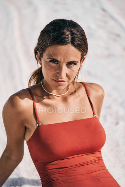 Tanned young woman in red swimsuit relaxing on salty lake shore — Stock Photo
