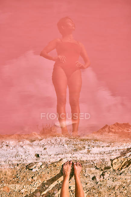 Slim female in swimwear with hands on waist while reflecting in pink water of red lagoon — Stock Photo
