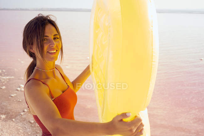 Sensual female with inflatable mattress resting on beach — Stock Photo
