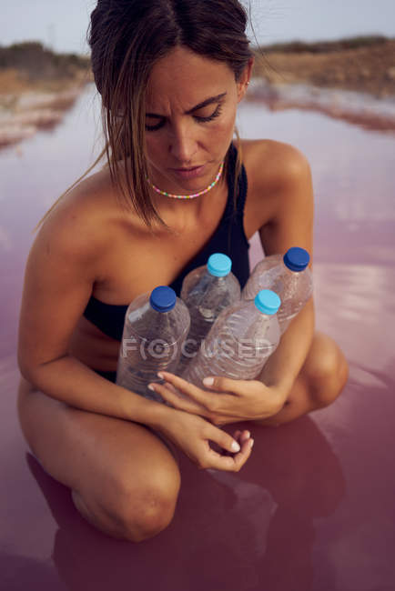 Preoccupato femmina in costume da bagno raccolta rifiuti nel lago naturale — Foto stock