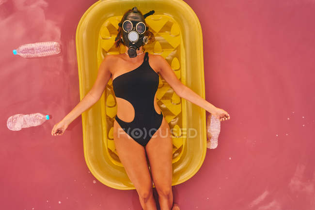 Female in gas mask and with plastic bottles in lake water — Stock Photo