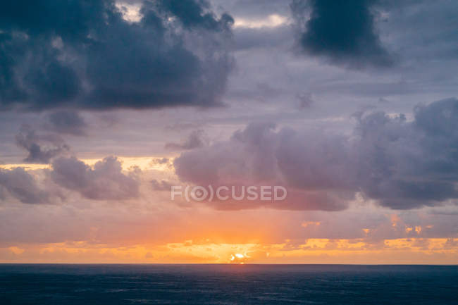 Coast with dry grass near stormy sea in cloudy evening during beautiful sunset — Stock Photo