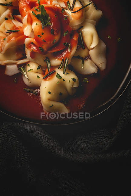 Готується равілі з томатним соусом і травами в чаші біля виделки і серветки на столі. — стокове фото