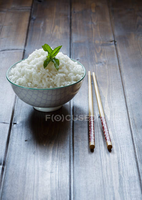 Schüssel mit traditionellem japanischen Reis und Stäbchen auf Holztisch. — Stockfoto