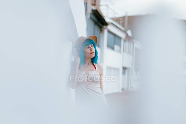 Mulher relaxada com cabelo azul em chapéu e sundress passeando ao longo da rua da cidade no dia de verão — Fotografia de Stock