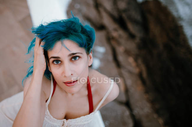 Sensual carefree woman leaning on pier with back and stretching hand to waterfront — Stock Photo