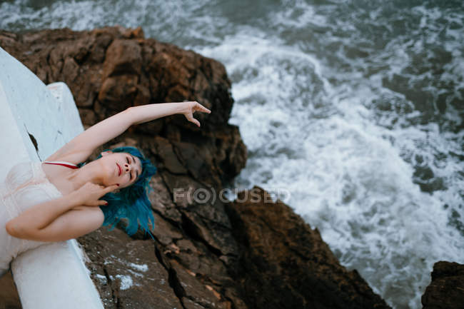 Sinnliche unbeschwerte Frau, die sich mit dem Rücken auf einen Steg lehnt und die Hand zum Wasser ausstreckt — Stockfoto