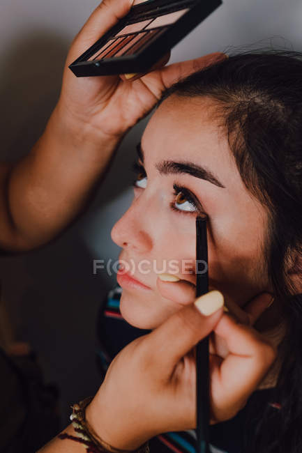 Beautiful young woman getting makeover by professional makeup artist in salon — Stock Photo