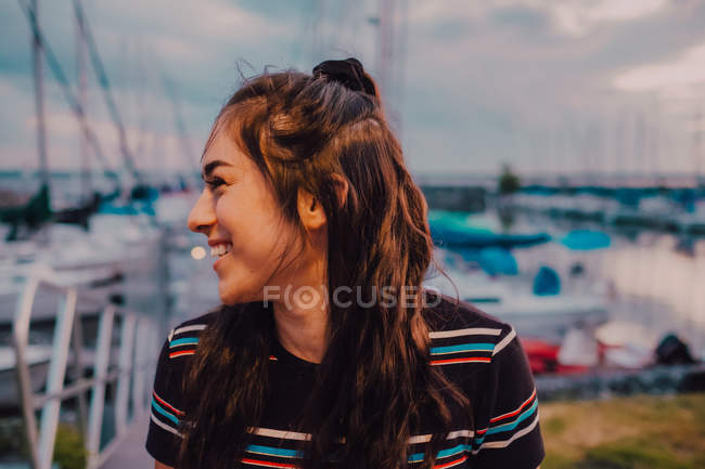 Glückliche junge tätowierte Frau im Kleid, die auf einem Kai steht, der mit Yachten und Booten gefüllt ist — Stockfoto