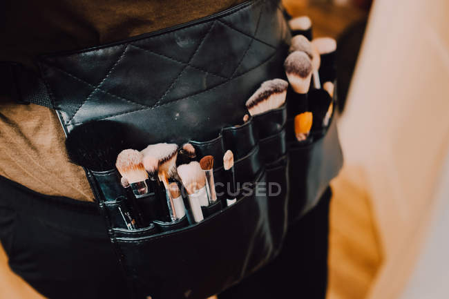 Maquilleur portant un sac de tablier avec diverses brosses pour le travail — Photo de stock