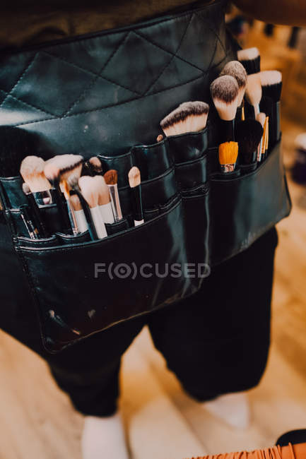 Artista del trucco che indossa borsa di grembiule con vari pennelli per il lavoro — Foto stock