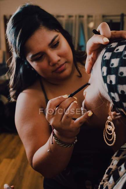 Attraktive erwachsene schwarze Frau trägt Lidschatten von professionellem Maskenbildner im Atelier auf — Stockfoto
