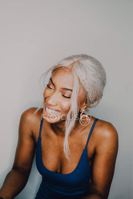 Fröhliche erwachsene Afroamerikanerin mit blonden Haaren, die blaue und geschlossene Augen trägt — Stockfoto