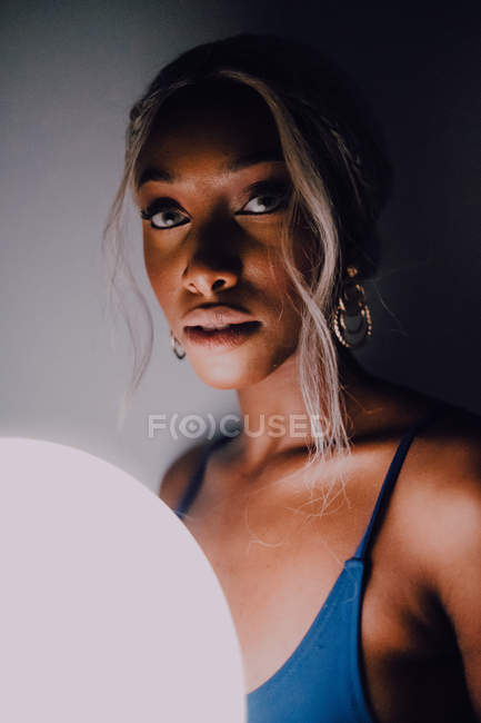 Attractive Black adult woman with white illuminated balloon in dark looking at camera — Photo de stock