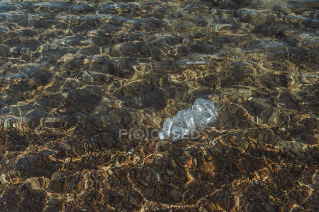 Frasco de plástico vazio amassado em água — Fotografia de Stock