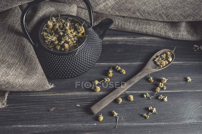 Dried daisy heap in wooden spoon on dark table for tea making — Stock Photo