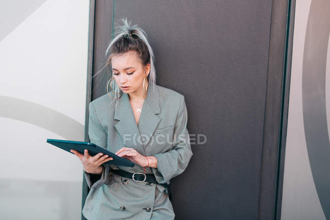 Empresária com penteado na moda e terno usando laptop na parede — Fotografia de Stock