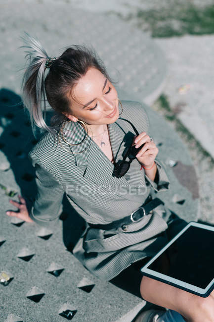 Стильная деловая женщина, работающая на планшете, сидящая на квадратной тарелке и закрытые глаза, наслаждаясь солнцем — стоковое фото