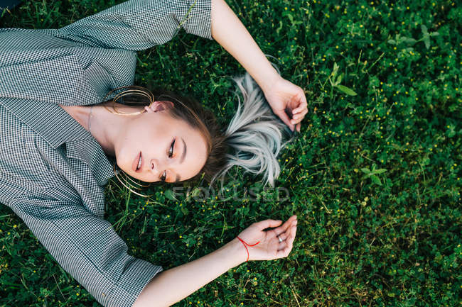 Draufsicht der trendigen Geschäftsfrau, die sich ausruht, die Hände hebt und auf grünem Gras liegt — Stockfoto