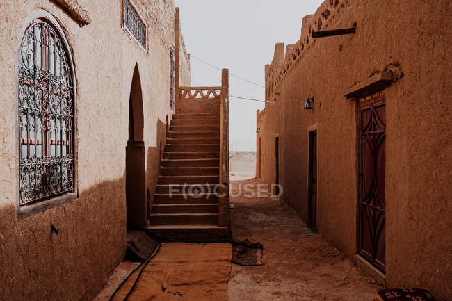 Esterno di vecchie case arabe tradizionali con scala e finestre ornamentali sulla strada stretta della città in Marocco — Foto stock