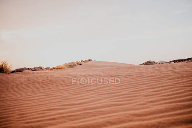 Cielo nuvoloso soleggiato su colline e rocce nel deserto arido la sera in Marocco — Foto stock