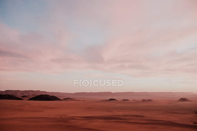 Nuageux coucher du soleil sur collines et rochers dans un désert aride en soirée au Maroc — Photo de stock