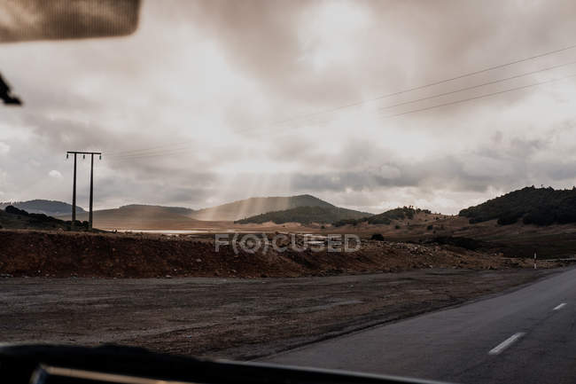 Асфальтовая дорога, проходящая по обочинам перед машиной в пасмурный день в Моро — стоковое фото